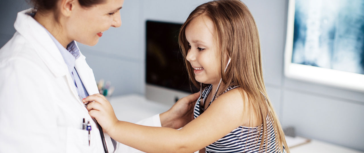 Ein kleines Mädchen darf mit dem Stethoskop das Herz der Ärztin abhören.