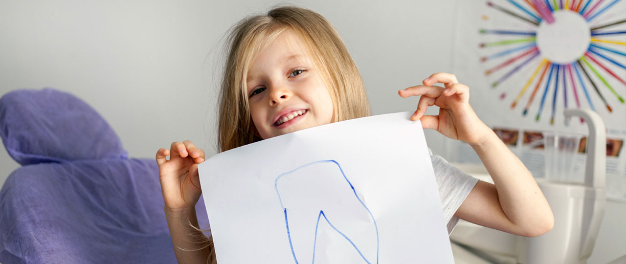 Kleines Mädchen beim Zahnarzt hält die Zeichnung eines Zahns in die Kamera.