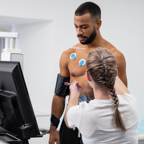Ein Mann wird bei einer sportmedizinischen Untersuchung für ein Balstungs-EKG verkabelt.